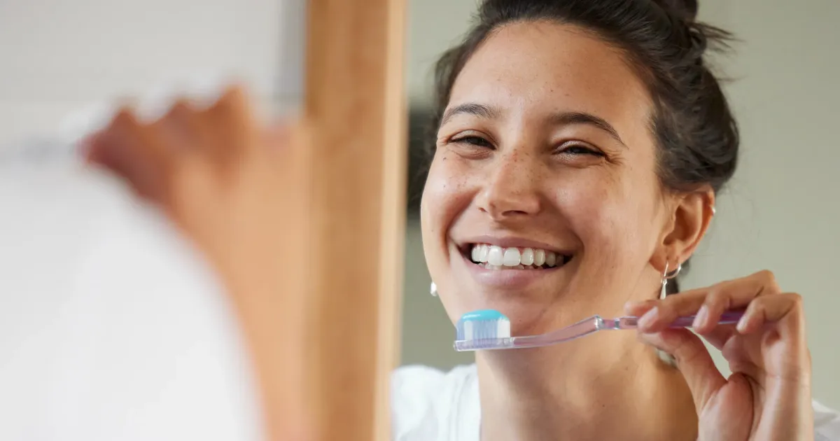 Una mujer se está por cepillar los dientes luego de usar alineadores