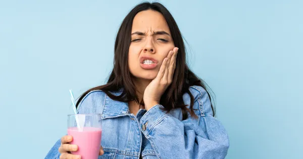 Una mujer toma algo frio que le produce sensibilidad dental